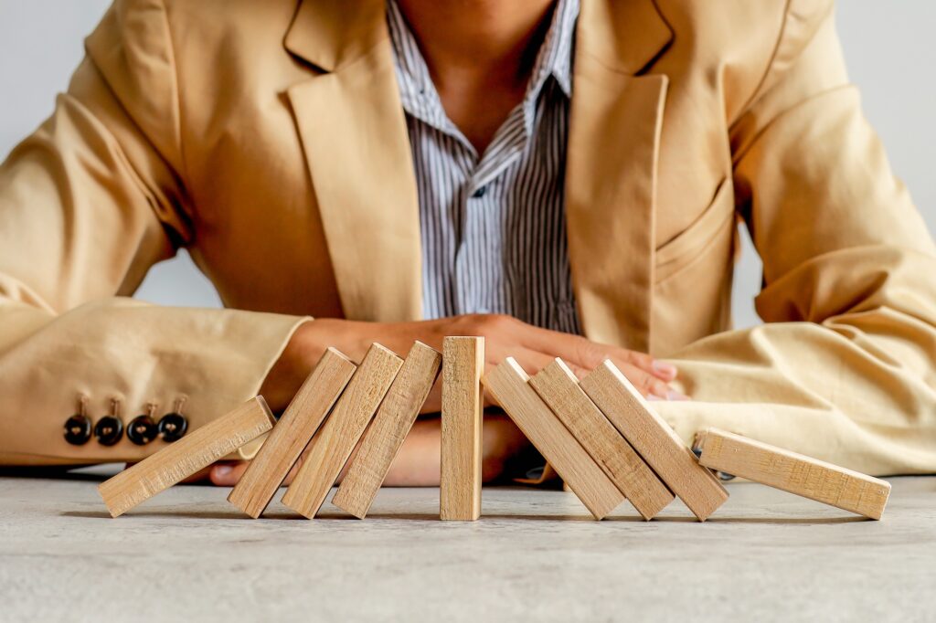 Businessman Watches Symmetrical Domino Effect Pause, Illustrating Intervention And Stability