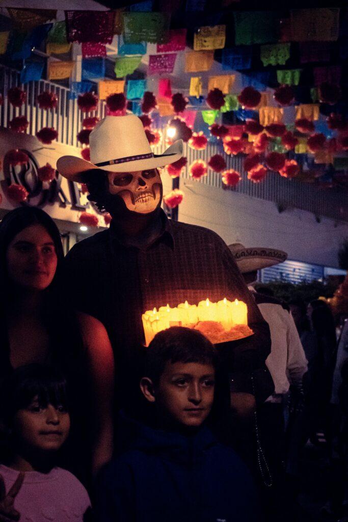 Vibrant Day of the Dead festival with traditional costumes and candles in Tlaquepaque, Mexico.