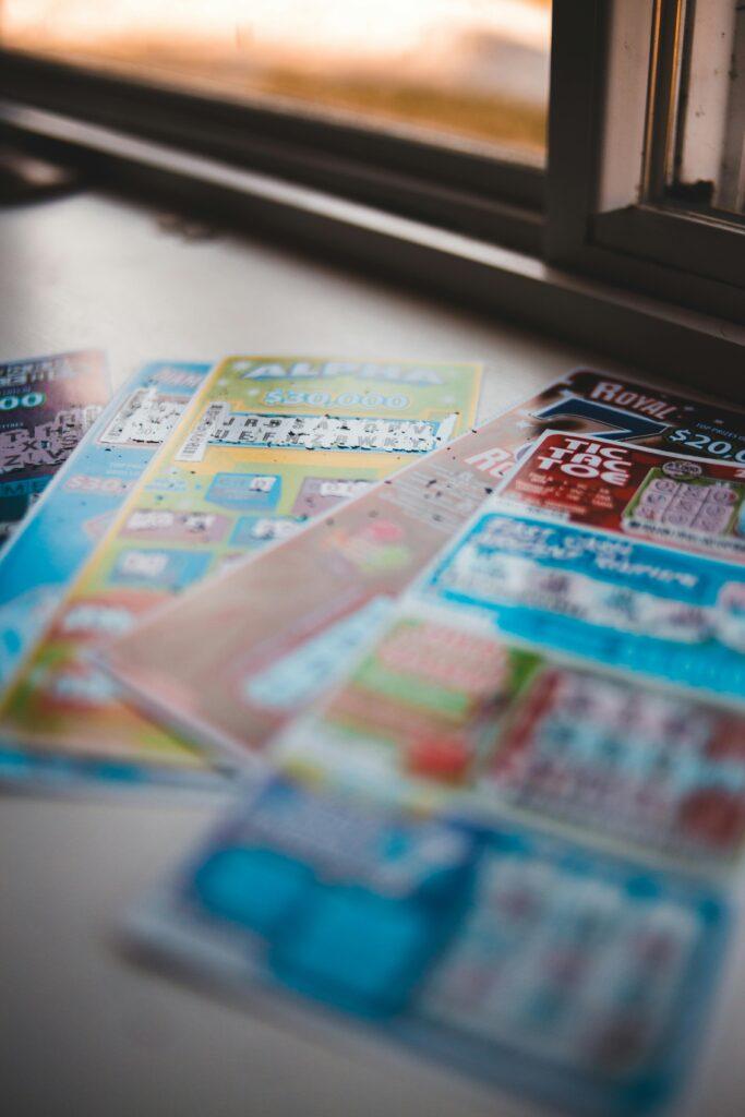 Vivid close-up of assorted lottery tickets on a table near a window, showcasing gambling concepts.