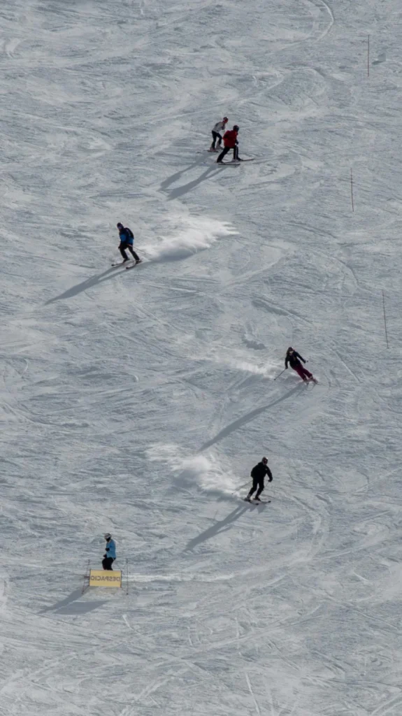 A group of skiers enjoy a thrilling descent on a snowy mountain slope under the sun.