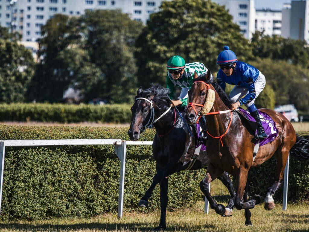 Two jockeys race fiercely in a horse racing event on a sunny day.