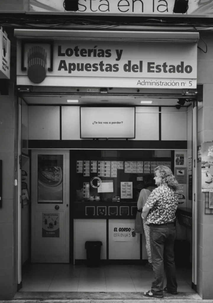 A candid black and white capture of people waiting outside a lottery kiosk.