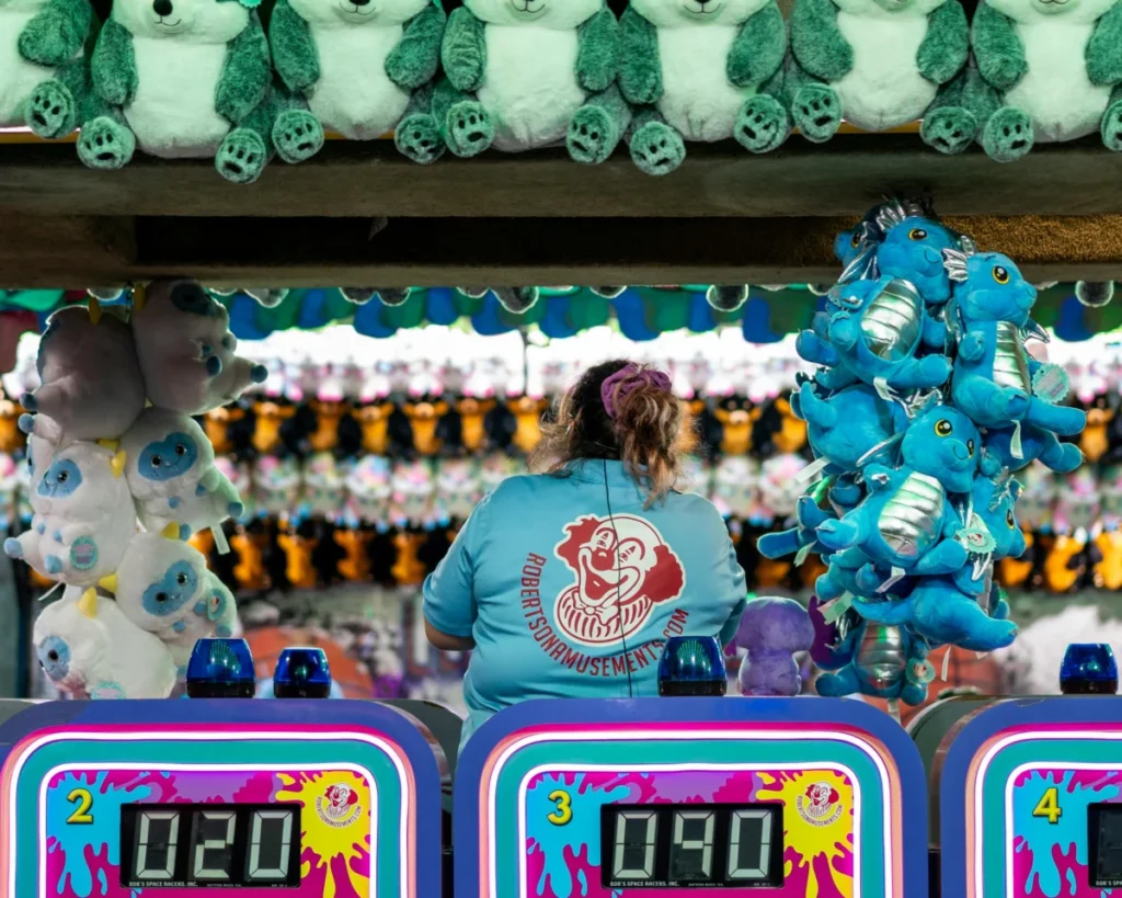 Colorful amusement fair game booth with vibrant plush toys and digital scoreboards in Ottawa, Canada.