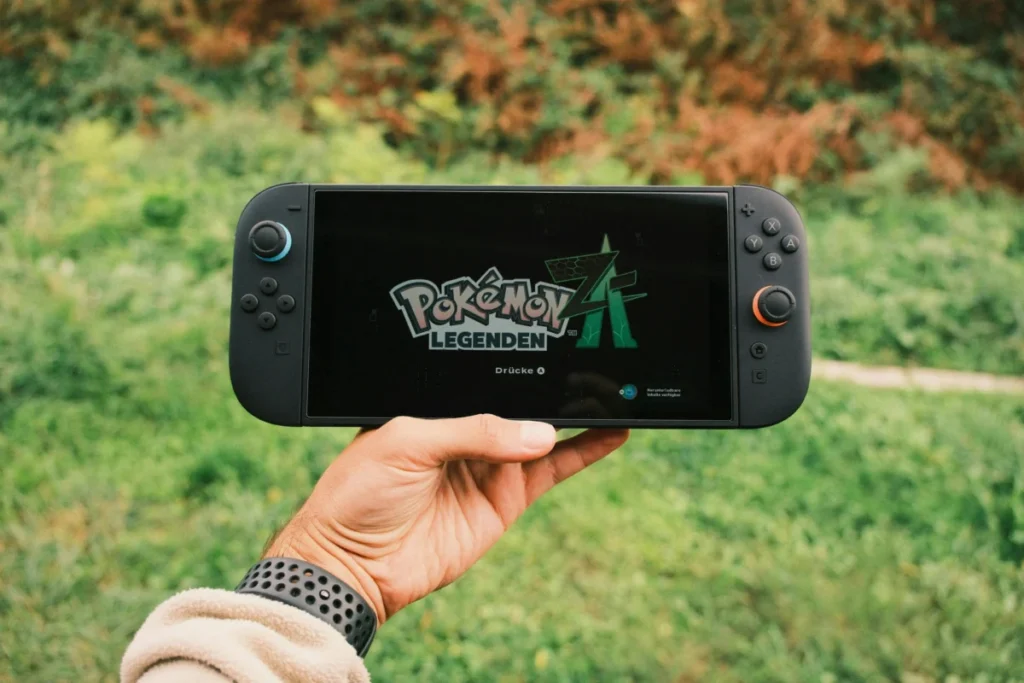Découvrez l’astuce incontournable pour acquérir la Nintendo Switch au tarif le plus avantageux en janvier 2026 ???? A hand holding a handheld gaming console displaying the Pokémon Legends game screen outdoors.