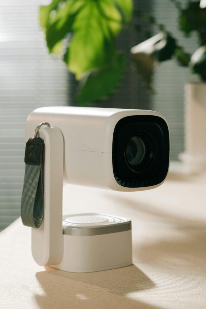 Un vidéoprojecteur révolutionnaire : 4K, écran géant de 200 pouces, 3D et abordable, il explose les attentes sur Kickstarter Sleek white projector with a strap on a desk, perfect for office or home use.