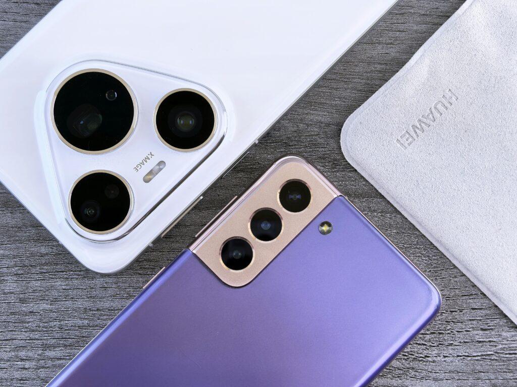 Close-up of two smartphones with camera focus on a textured wooden surface.