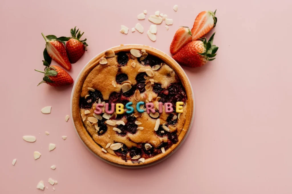 Delicious strawberry cake decorated with colorful subscribe letters and almond slices.