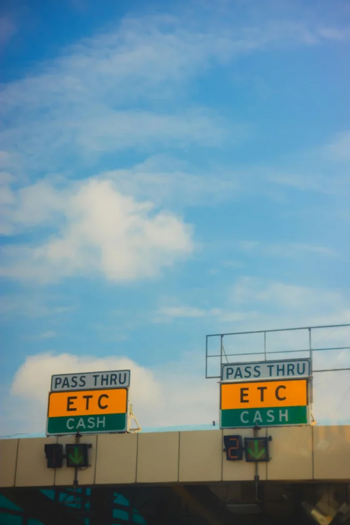 Automated toll booths with ETC pass signs under a vibrant blue sky.