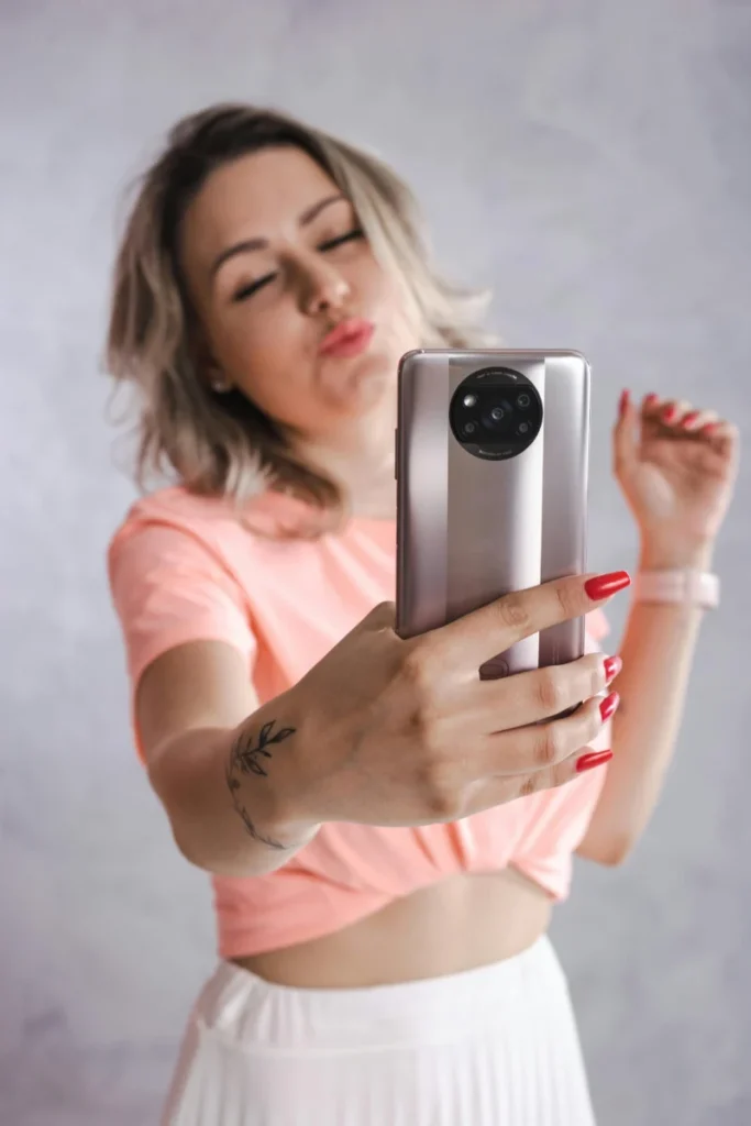 Promo exceptionnelle : Xiaomi déstocke massivement ses Smart TV A 65 à prix coûtant ???? Woman taking a selfie with a smartphone, showcasing modern lifestyle and technology.
