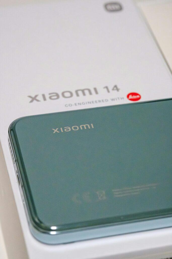 Close-up view of a green Xiaomi 14 smartphone placed on its original packaging box with visible branding.